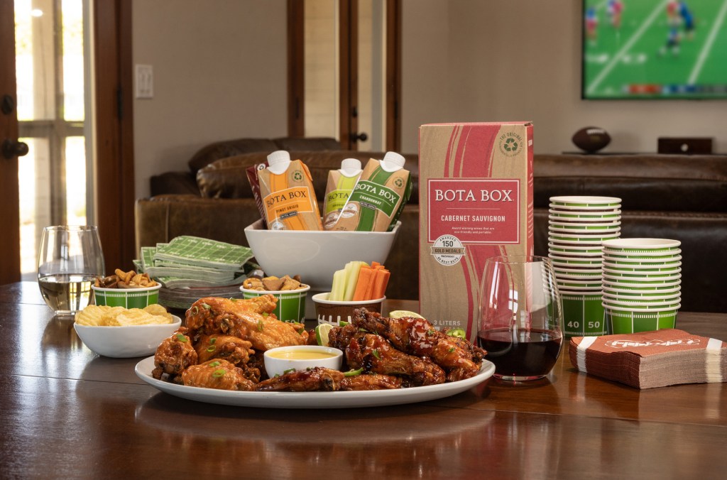 Photo of Bota Box Cabernet Sauvignon 3L on a table with BBQ chicken wings and football themed sides