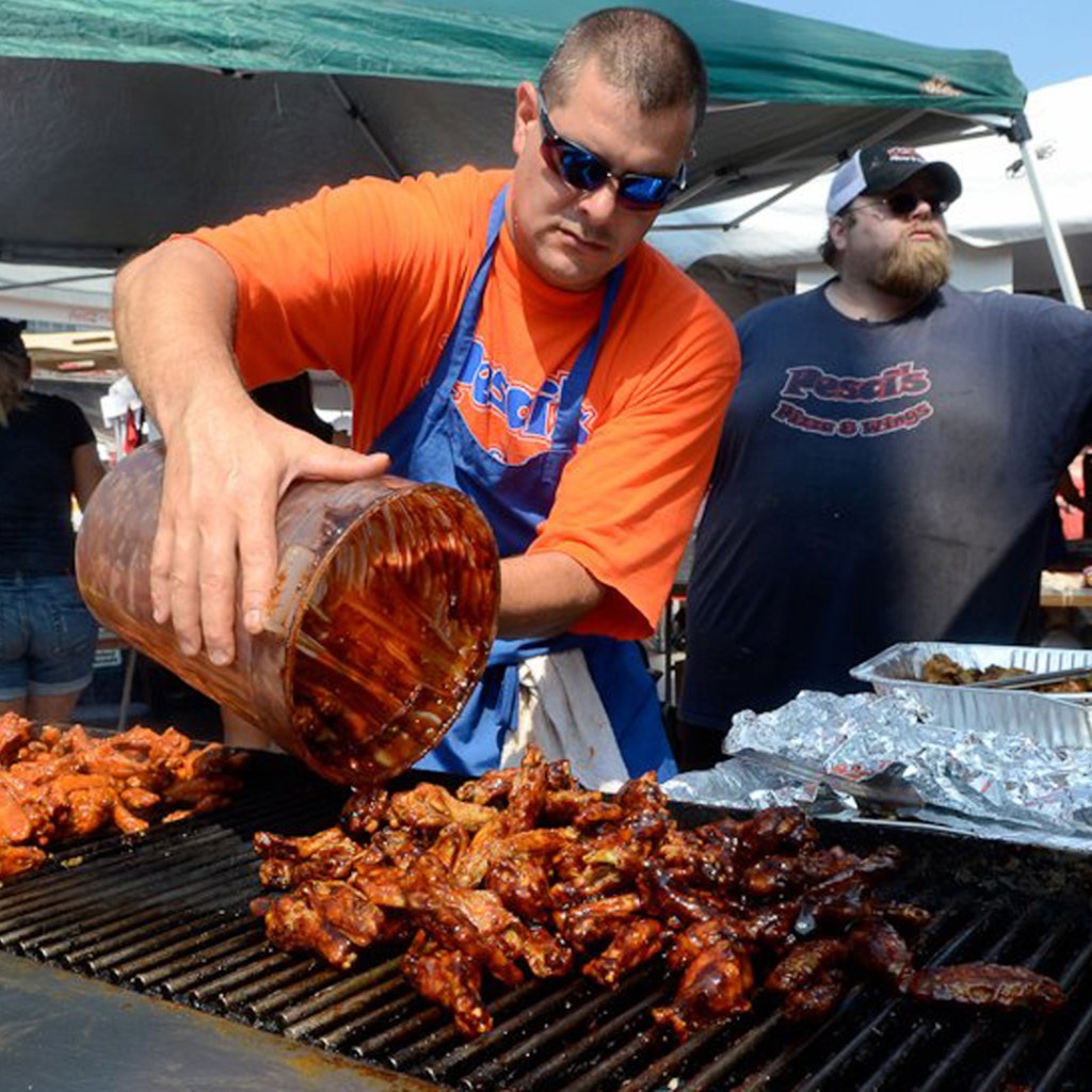 Photo of man cooking chicken wings on an outdoor grill